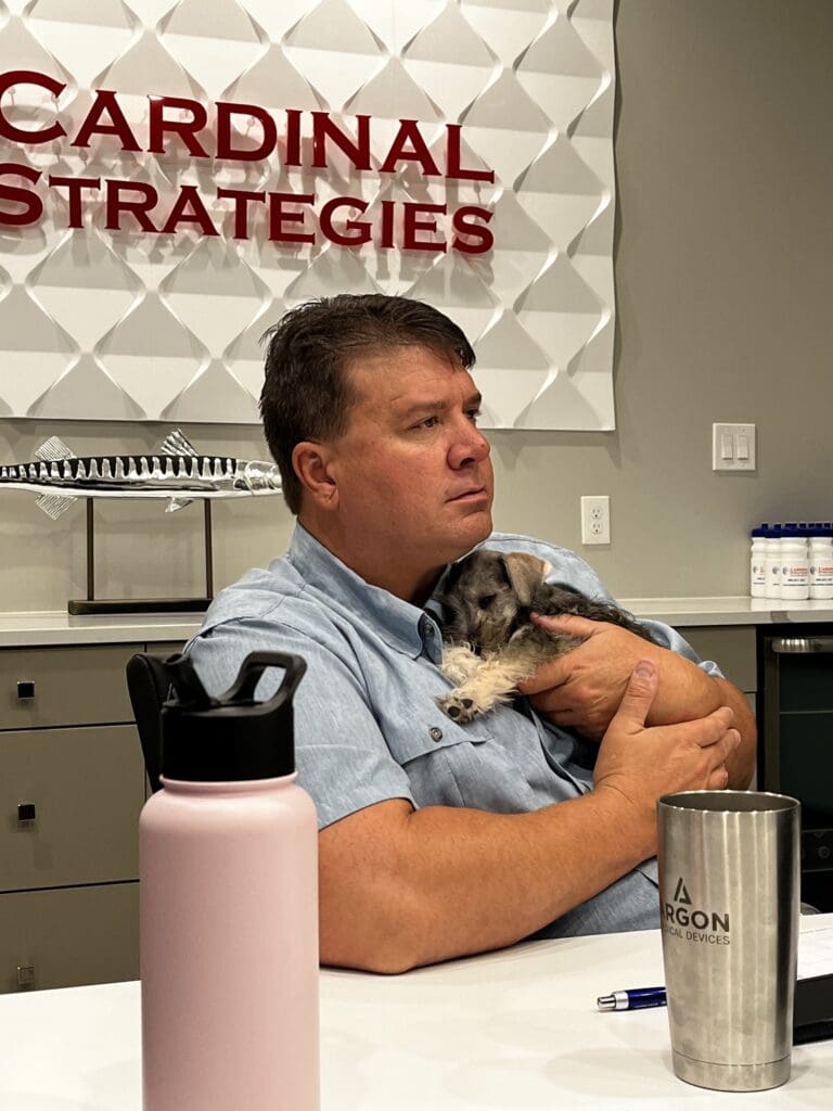 Mike from Cardinal Strategies holding a dog in the conference room.