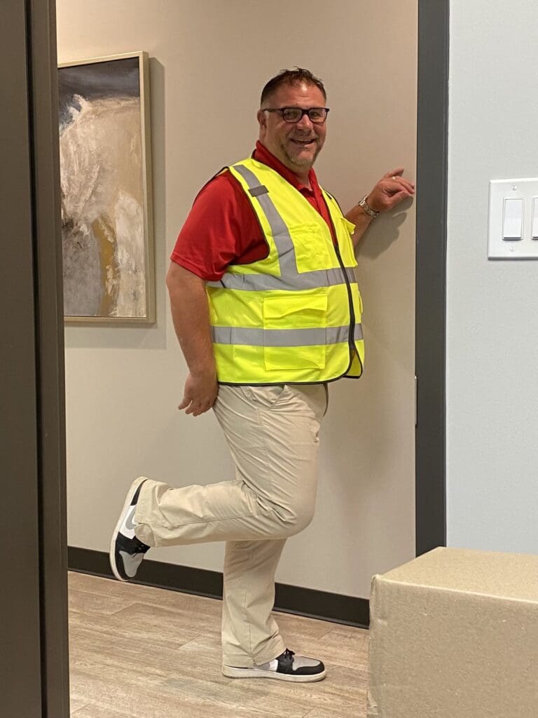 Tim Litte from Cardinal Strategies smiling in the office with a reflective vest.