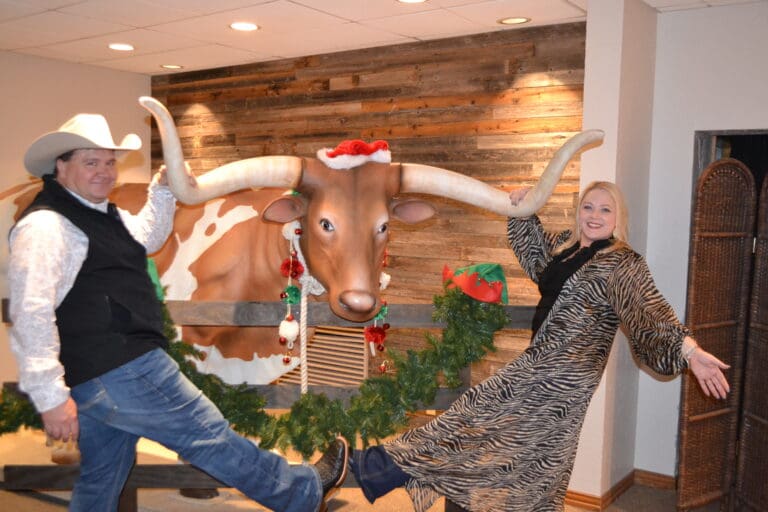 Michael and Kim from Cardinal Strategies posing in front of a bull at the company Christmas party.