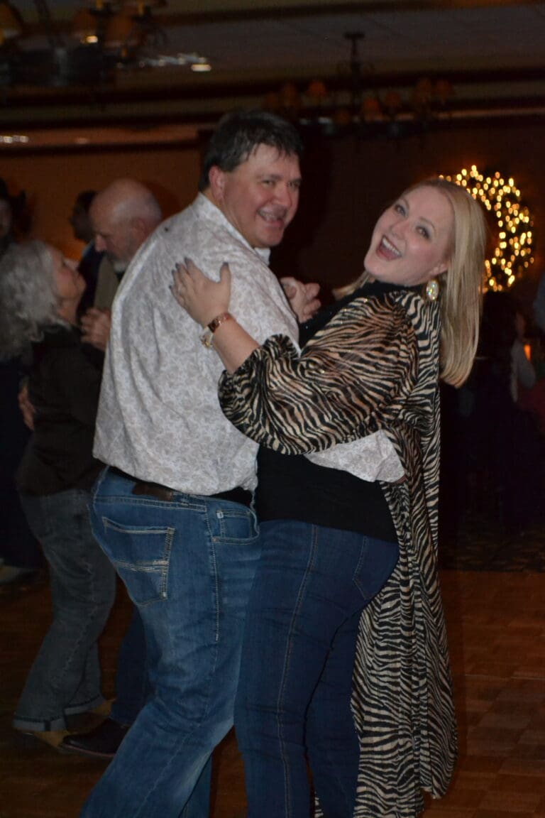 Kim and Michael from Cardinal Strategies smiling and dancing at a company Christmas party.