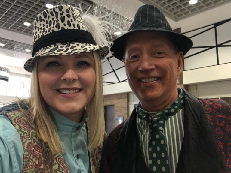 Kim and Stan from Cardinal Strategies with fedoras on