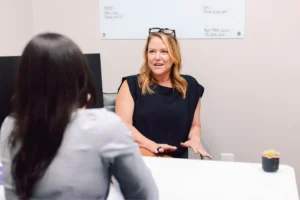 Home page. Amy sitting talking to Brittany in office at Cardinal Strategies