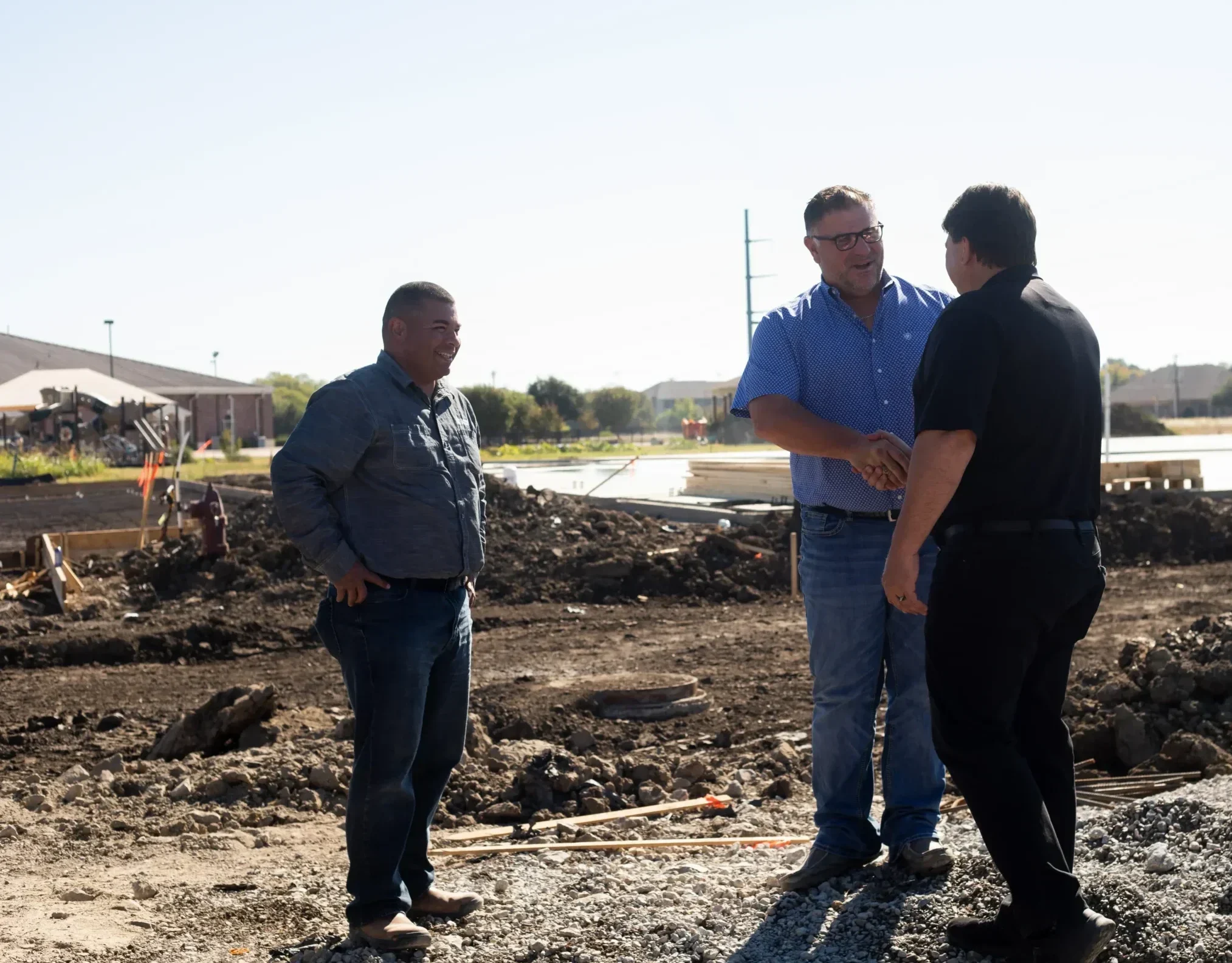 Three Cardinal Strategies workers on construction site visit, two of them are shaking hands